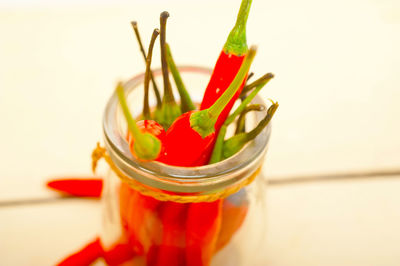 Close-up of red chili peppers in glass container on table