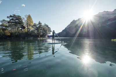 Germany, bavaria, garmisch partenkirchen, young woman stand up paddling on lake eibsee