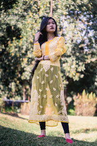 Young woman standing against yellow and trees