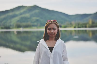 Portrait of young woman standing against lake