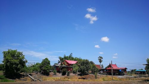 Houses and trees on field against sky