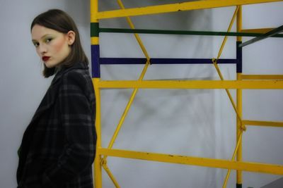 Portrait of young woman standing against wall