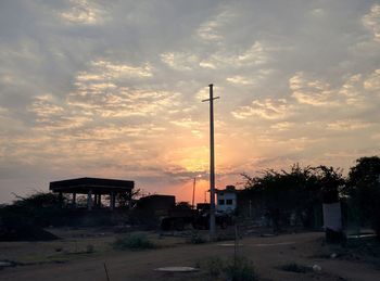 Silhouette plants by building against sky during sunset
