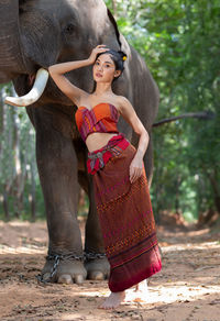Portrait of young woman standing by elephant
