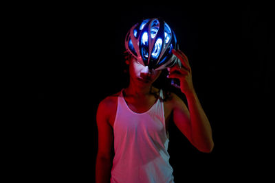 Man holding illuminated cycling helmet in darkroom