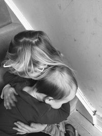 High angle view of siblings embracing while sitting on steps