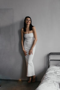 Portrait of young woman standing against wall