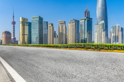 City street by modern buildings against clear sky