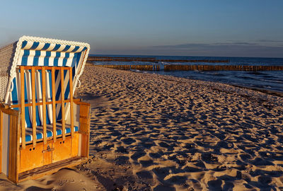 Hooded chairs on beach against clear sky