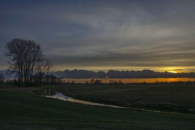 Scenic view of farm against sky during sunset