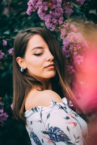 Portrait of beautiful woman standing by flowering plant