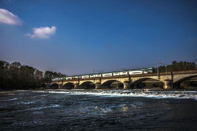 Bridge over river against blue sky during winter