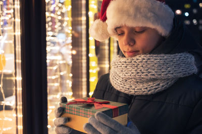 Boy wearing scarf holding gift box at home