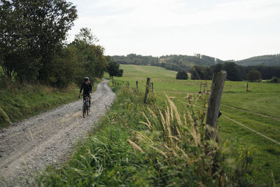 Cyclist on a gravel road between fields.