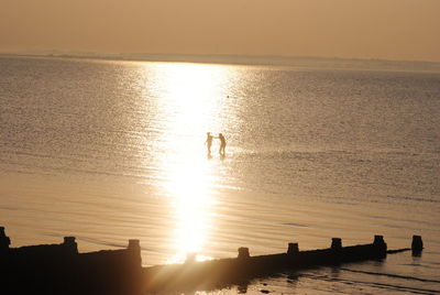 Silhouette man standing on beach against clear sky during sunset