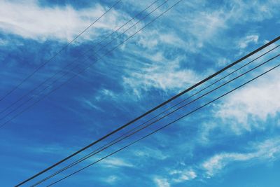 Low angle view of electricity pylon against cloudy sky