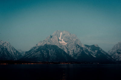 Scenic view of lake by snowcapped mountains against sky