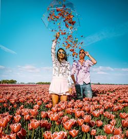 Couple standing amidst tulip farm with umbrella