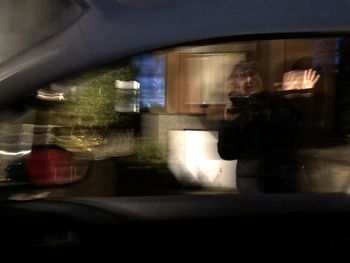 Reflection of man photographing in car window