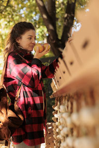 Side view of young woman standing against christmas tree