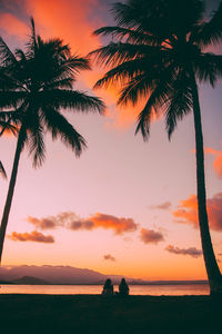 Silhouette palm trees on beach against sky during sunset