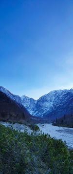 Scenic view of snowcapped mountains against blue sky