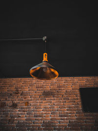 Low angle view of lighting equipment against brick wall