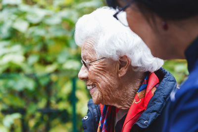 Side view of happy senior woman with caretaker in park