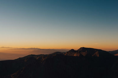 Scenic view of silhouette mountains against clear sky during sunset