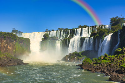 Scenic view of waterfall against clear blue sky