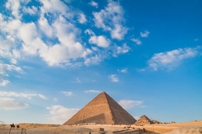 Tourists in a row of a desert, pyramids 