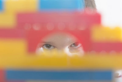 Cropped portrait of boy looking through colorful toy blocks