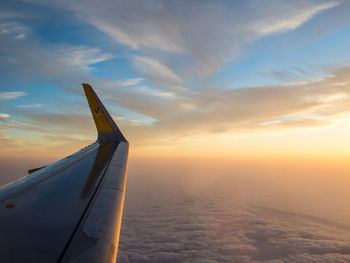 Cropped image of aircraft wing against sky during sunset