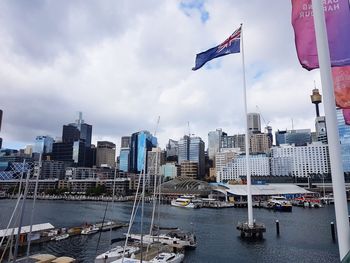 Sailboats in city by buildings against sky