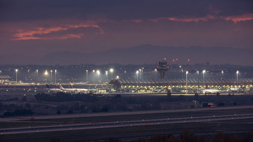 Over view of airport terminal at night. lights illuminate the planes, control tower and apron. 