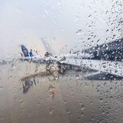 Close-up of wet car window against sky