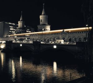 Illuminated bridge over river in city at night