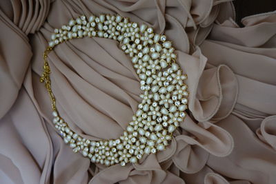 High angle view of diamond and pearl necklace on dress