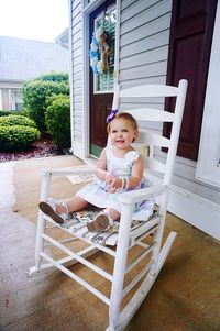 Portrait of cute girl sitting on chair at home