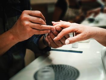 Midsection of man giving manicure to woman