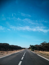 Empty road along landscape against blue sky
