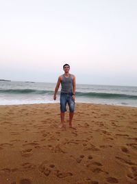 Full length portrait of man standing on beach against sky