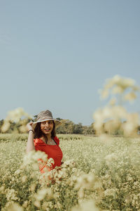 Portrait of young woman wearing hat on field against clear sky