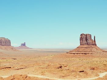 Scenic view of arid landscape against clear blue sky