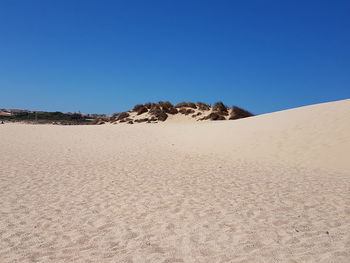 Sand dunes in desert against clear blue sky