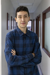 Portrait of young man standing against wall