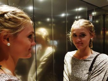 Young woman reflecting on mirror in elevator