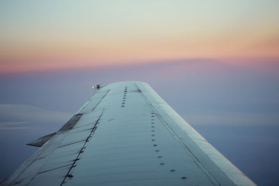 Airplane flying over sea against sky during sunset