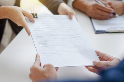Midsection of woman holding paper with text on table