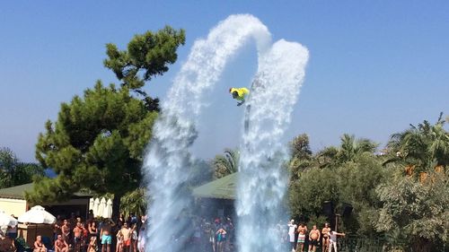 People enjoying at fountain against trees